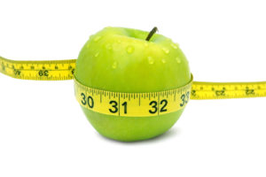 Green apple with red measuring tape and water drops.